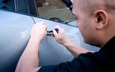 Auto locksmith unlocking car door during emergency lockout service